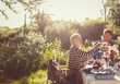 © Paul Bradbury/Caia Image - Couple toasting wine glasses at sunny garden party patio table