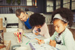 © Paul Bradbury/Caia Image - Multi-ethnic father and daughters coloring in kitchen