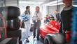 © Chris Ryan/Caia Image - Manager and formula one race car driver talking in repair garage