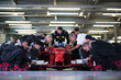 © Chris Ryan/Caia Image - Pit crew preparing formula one race car and driver in repair garage