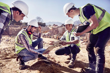 Construction Workers Engineers Using Digital Tablets At Sunny Construction Site