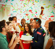 © Robert Daly/Caia Image - Enthusiastic family with birthday cake throwing confetti