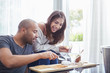 © Trevor Adeline/Caia Image - Smiling couple drinking white wine eating crackers cheese in living room