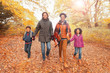 © Robert Daly/Caia Image - Portrait smiling young family holding hands walking on path in autumn park