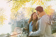 © Tom Merton/Caia Image - Smiling young couple bicycle on bridge over sunny autumn canal in Amsterdam