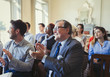 © Paul Bradbury/Caia Image - Smiling business people clapping in business conference audience