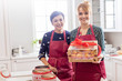 © Agnieszka Olek/Caia Image - Portrait smiling female caterers showing wrapped box of pastries in kitchen
