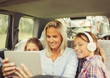 © Paul Bradbury/Caia Image - Mother daughters watching video on digital tablet in back seat of car