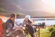 © Trevor Adeline/Caia Image - Smiling young couple drinking coffee at sunny lakeside campsite