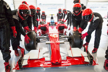 Pit Crew Pushing Formula One Race Car Into Repair Garage
