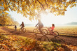 © Robert Daly/Caia Image - Young family bike riding in sunny autumn park