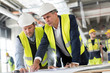 © Agnieszka Olek/Caia Image - Male engineers viewing blueprints at construction site