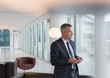 © Martin Barraud/Caia Image - Businessman texting with cell phone in lounge