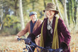 © Paul Bradbury/Caia Image - Smiling senior couple bike riding in sunny autumn woods