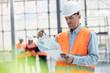 © Rafal Rodzoch/Caia Image - Male engineer reviewing blueprints on clipboard at construction site