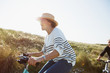 © Sam Edwards/Caia Image - Playful mature woman riding bicycle on sunny beach grass path