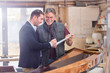 © Agnieszka Olek/Caia Image - Male customer signing paperwork for finished wood kayak in workshop