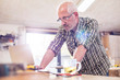 © Agnieszka Olek/Caia Image - Serious senior male carpenter using laptop in workshop