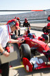 © Sam Edwards/Caia Image - Manager stopwatch timing pit crew replacing tires on formula one race car in practice session pit lane