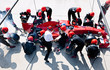 © Sam Edwards/Caia Image - Manager stopwatch timing pit crew replacing tires on formula one race car in pit lane
