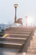 © Martin Barraud/Caia Image - Male runner tying shoe at sunny urban lamppost