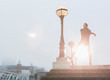 © Martin Barraud/Caia Image - Male runner stretching arms at sunny urban lamppost