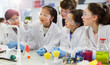 © Robert Daly/Caia Image - Curious students conducting scientific experiment, examining liquid in beaker in laboratory classroom
