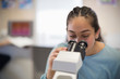 © Martin Barraud/Caia Image - Girl student using microscope in classroom