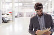 © Martin Barraud/Caia Image - Car salesman writing on clipboard in car dealership auto repair shop