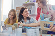 © Agnieszka Olek/Caia Image - Female instructor helping students painting picture frames in art class workshop