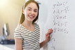 © Robert Daly/Caia Image - Portrait smiling, confident girl student solving physics equation at whiteboard in classroom
