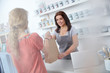 © Agnieszka Olek/Caia Image - Female business owner giving shopping bag to shopper in art paint shop