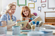 © Rafal Rodzoch/Caia Image - Female artists painting picture frames in art class workshop