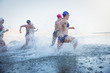 © Caiaimage/Sam Edwards/Caia Image - Female open water swimmers running and splashing in ocean surf