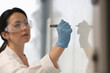 © Martin Barraud/Caia Image - Female science teacher wearing lab coat, rubber glove and goggles, writing at whiteboard in classroom