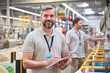 © Agnieszka Olek/Caia Image - Portrait smiling, confident male supervisor clipboard in fiber optics factory