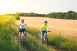 © sergo321 - young man and woman ride bicycles between fields in summer.
