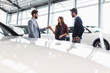 © Martin Barraud/Caia Image - Car salesman giving car keys to customers in car dealership showroom
