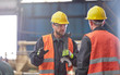 © Lukasz Olek/Caia Image - Male worker with large wrench talking to coworker in factory