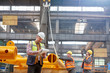 © Lukasz Olek/Caia Image - Male foreman with clipboard standing near workers in factory
