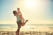 © Trevor Adeline/Caia Image - Playful boyfriend lifting girlfriend on sunny summer ocean beach