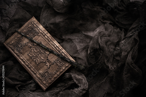 Cuadros en Lienzo Old book with spells and magic wand on gray background with witch rag