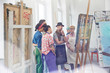 © Agnieszka Olek/Caia Image - Art students instructor examining, critiquing painting in art class studio