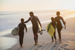 © Sam Edwards/Caia Image - Family surfers walking with surfboards on sunny summer sunset beach