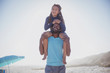 © Sam Edwards/Caia Image - Playful father carrying daughter on shoulders on sunny summer beach