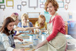© Agnieszka Olek/Caia Image - Portrait confident, smiling female art instructor helping students painting in art class workshop