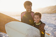 © Sam Edwards/Caia Image - Portrait smiling father son surfers carrying surfboards on sunny summer beach