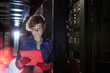 © Agnieszka Olek/Caia Image - Focused female IT technician using digital tablet in server room
