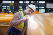 © Agnieszka Olek/Caia Image - Focused male engineer with flashlight examining equipment in factory