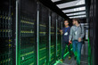 © Rafal Rodzoch/Caia Image - IT technicians walking and talking in dark server room